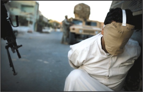 A man suspected of Mahdi Army activity is detained during a recent raid in Baghdad. General David Petraeus has singled out Ghazaliya,a mostly Sunni district in the western part of the city, as an area where the military has made progress. Photograph by Johan Spanner.